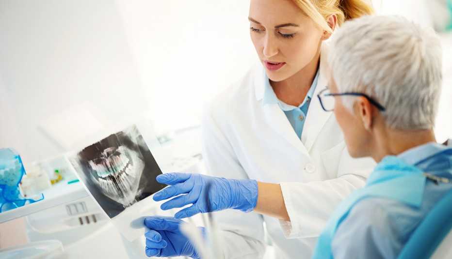 Female dentist examining a female patient. She's showing her dental x-ray image. Female dentist examining a female patient. She's showing her dental x-ray image.