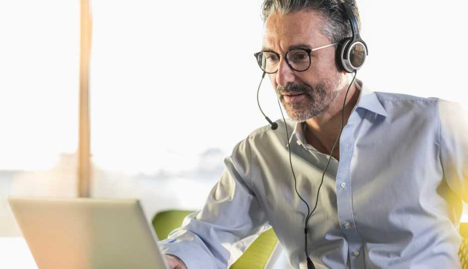 man wearing headset participating in videoconference call on laptop.