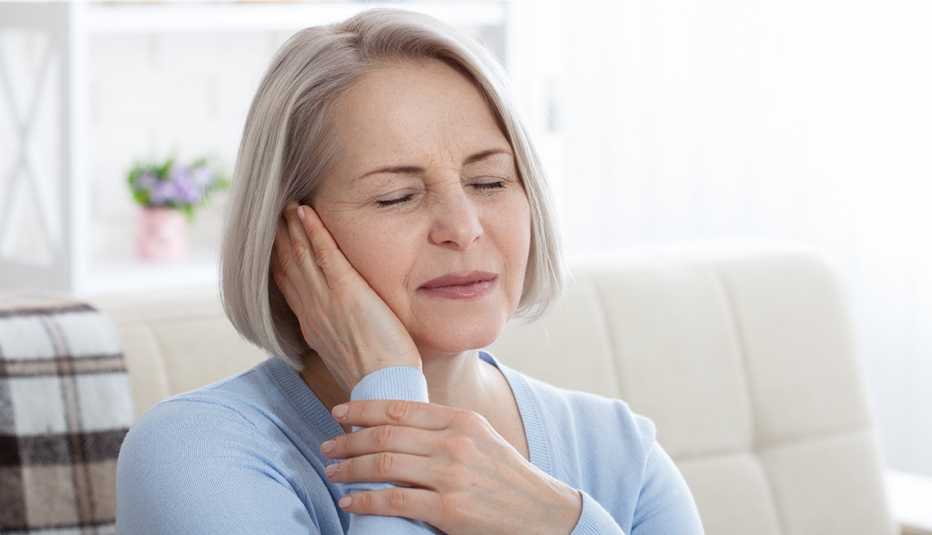 close up of a woman holding her ear, it looks like she is in pain