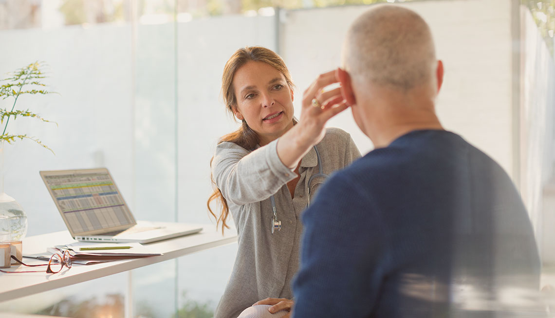 A doctor works with a patient trying out a hearing aid
