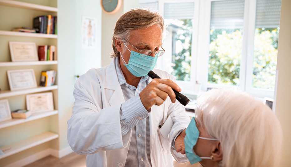 Doctor doing an eye exam on his patient, both wearing face masks