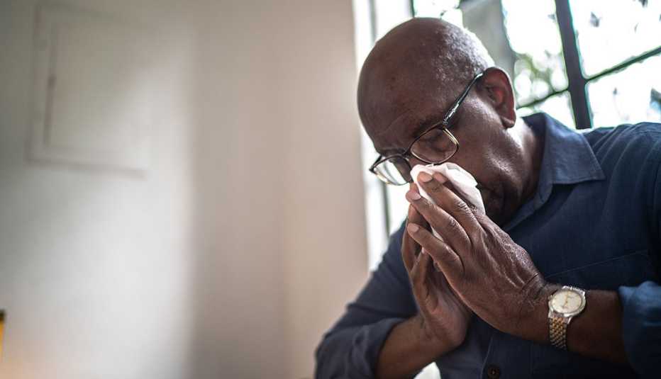 man sneezing into a tissue
