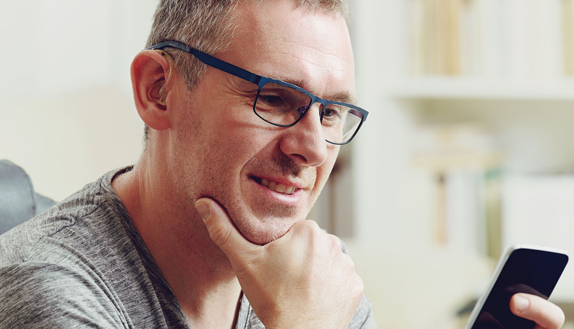 Man with hearing aid holds cell phone