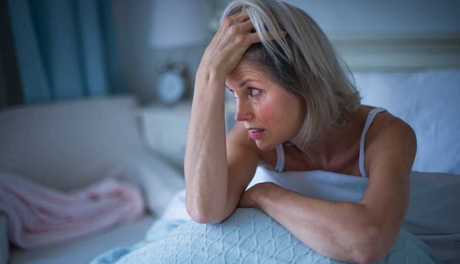 Senior woman sitting in bed and suffering from insomnia