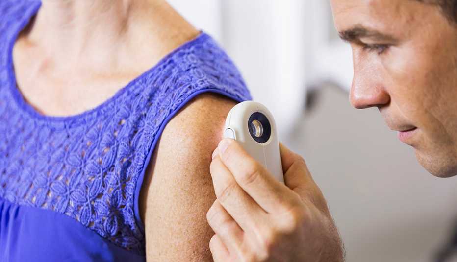 dermatologist examines woman's skin with a magnifying device