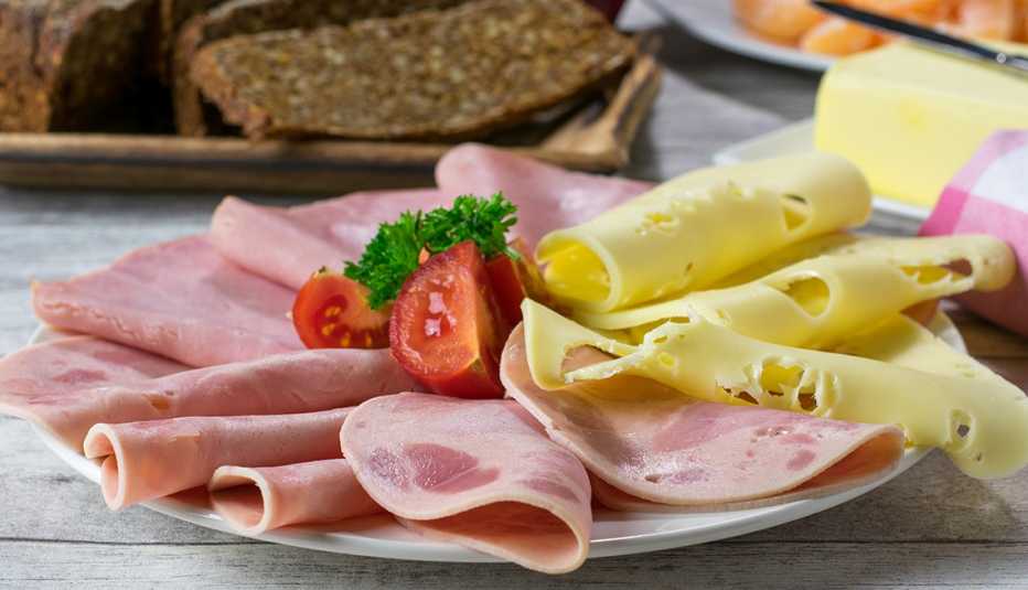 Traditional deli meats and cheeses with a cut tomato on a platter