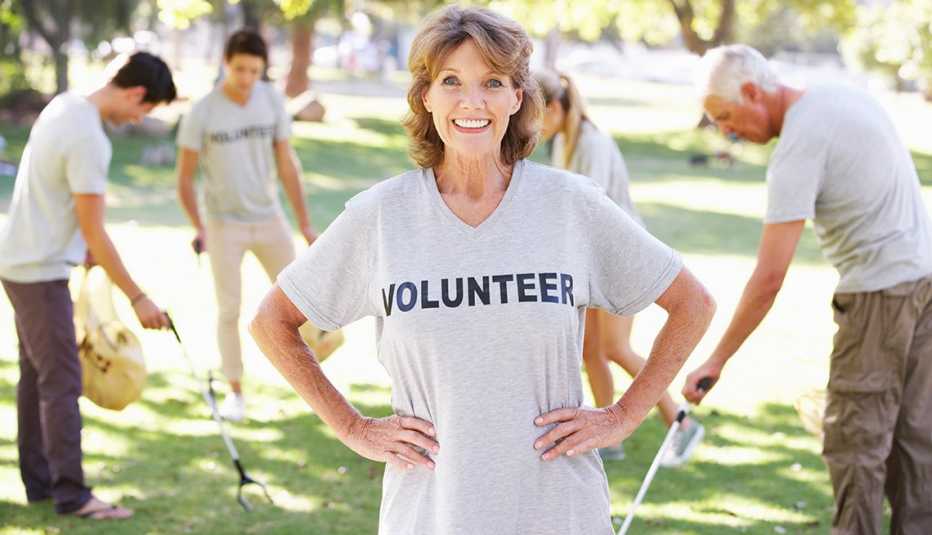 A volunteer group clearing litter in a park, a woman wearing a volunteer t-shirt