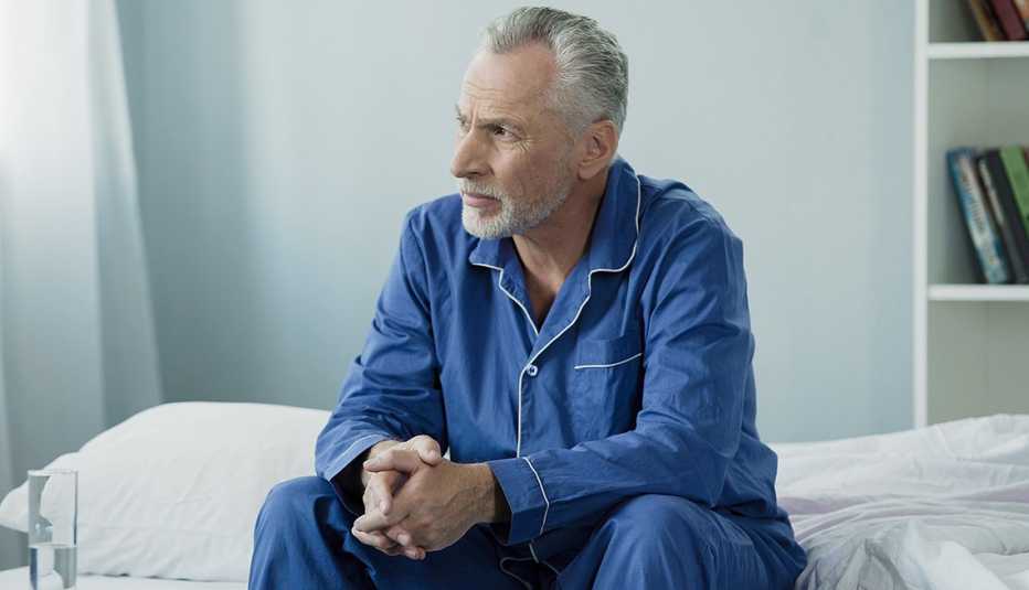 Man sitting on bed appearing upset. Man sitting on bed appearing upset.