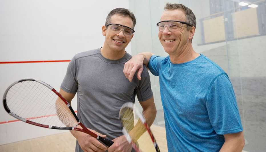 Portrait of smiling men holding squash rackets