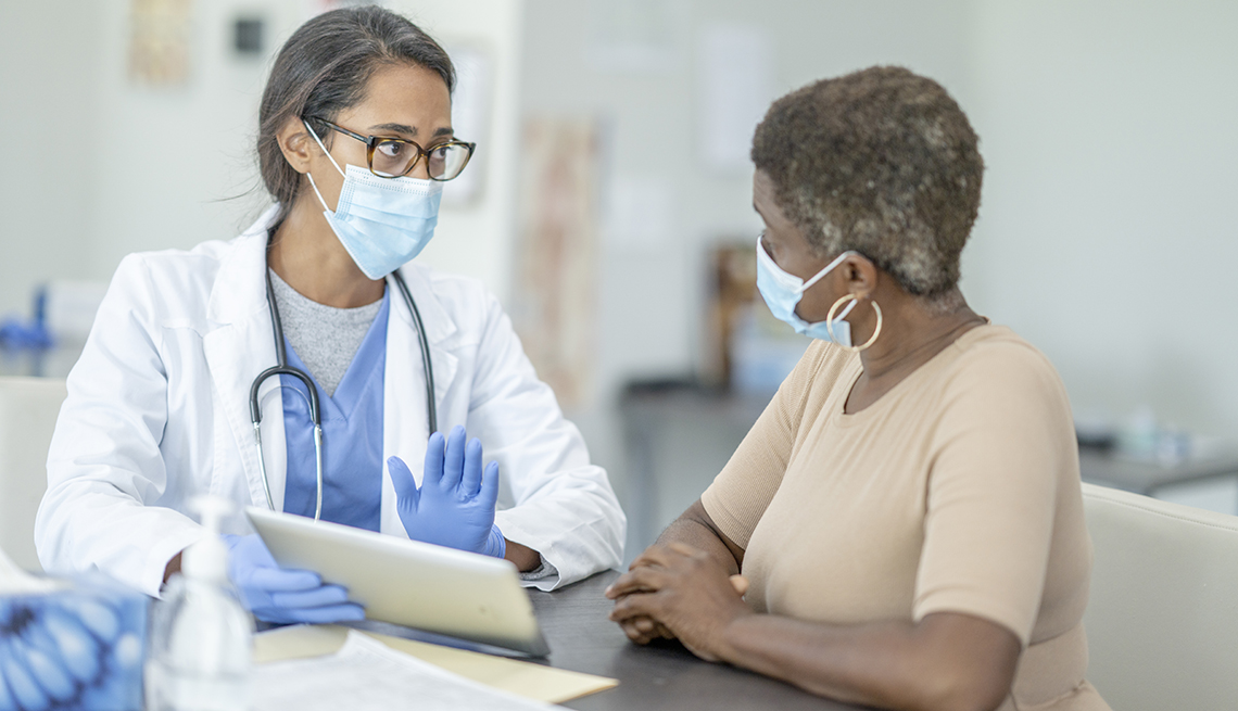 a woman talking to her female doctor about her mammogram results. both women are wearing face masks