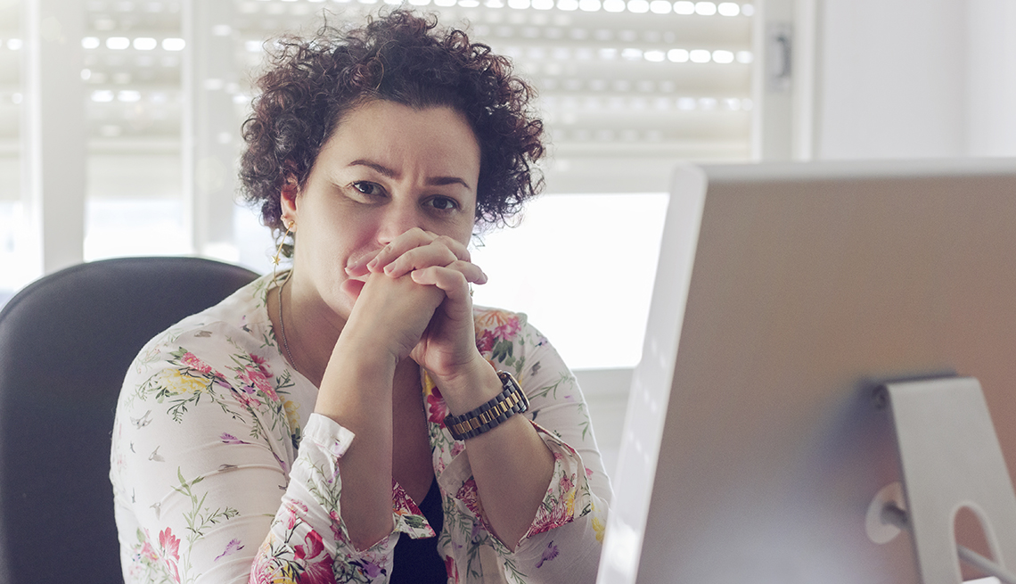 woman sitting at her desk, looking concerned