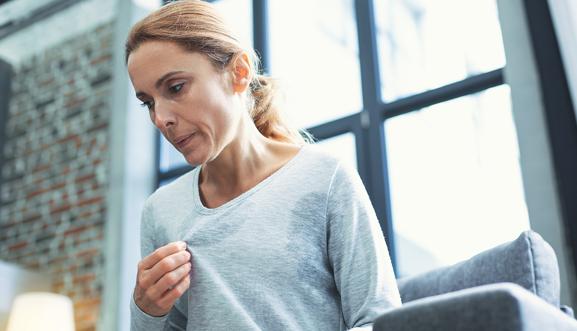 A woman touching her sweater and having hot flash