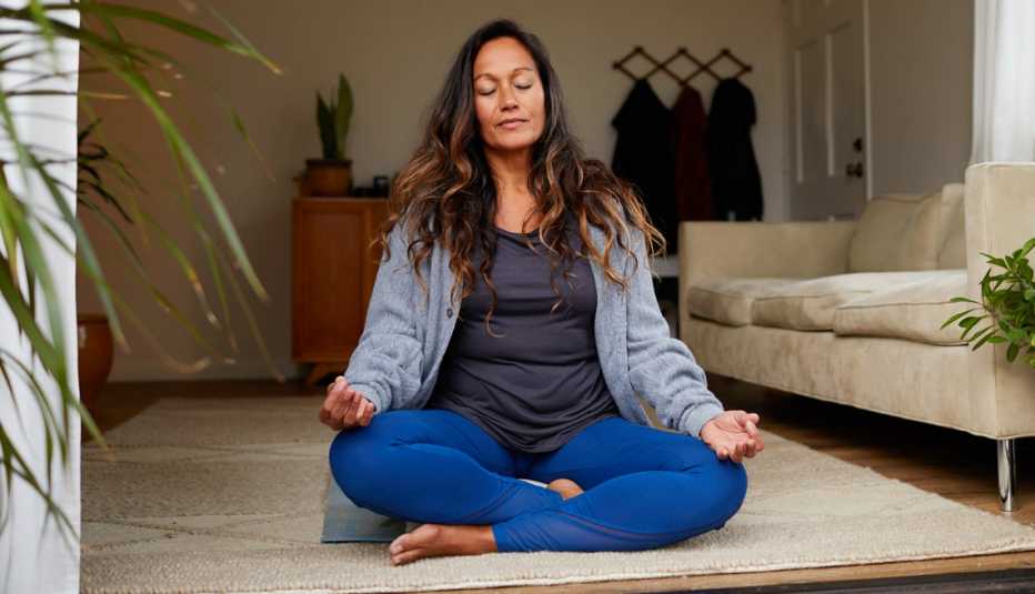 a woman sitting on the floor at home meditating