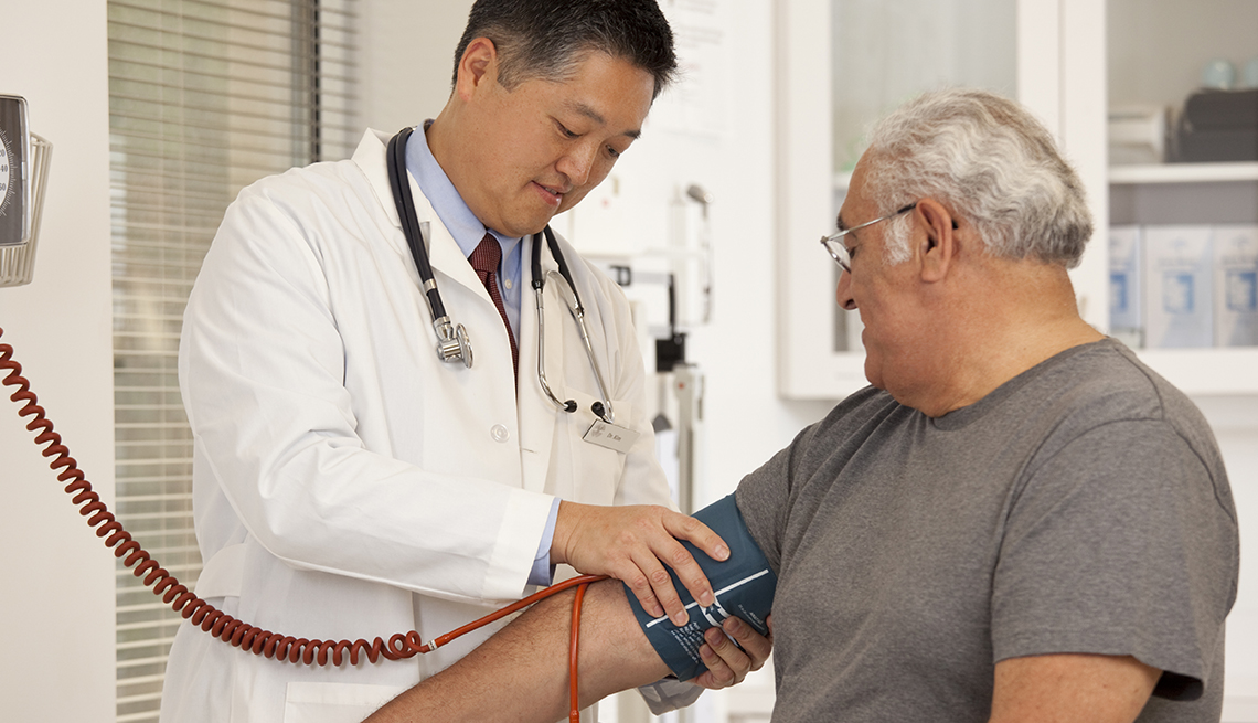 Older, overweight man gets his blood pressure checked by a physician