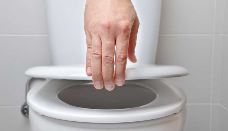 close up of a hand closing a toilet lid