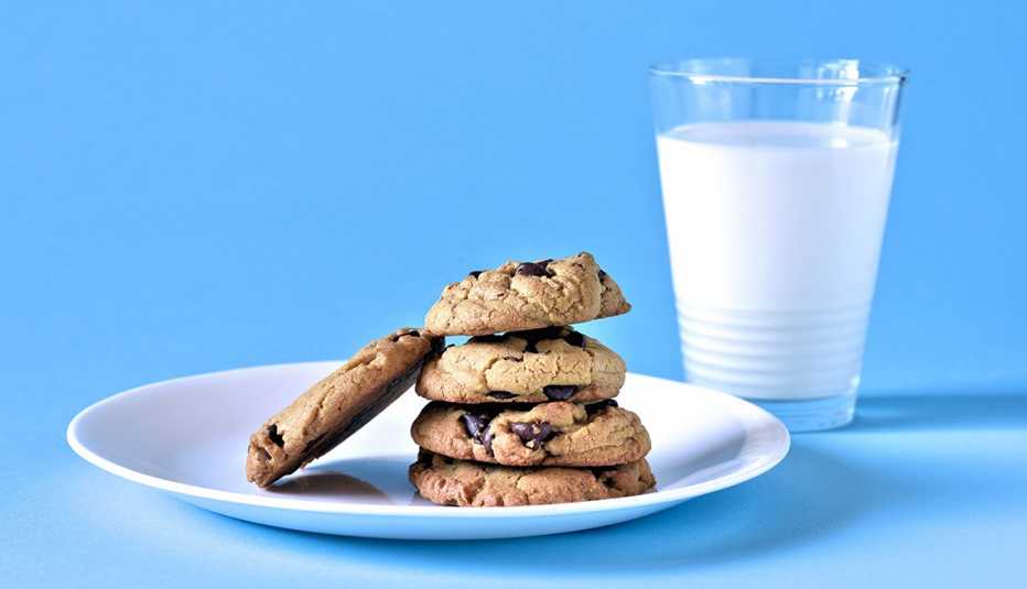plate of chocolate chip cookies and a glass of milk on blue background