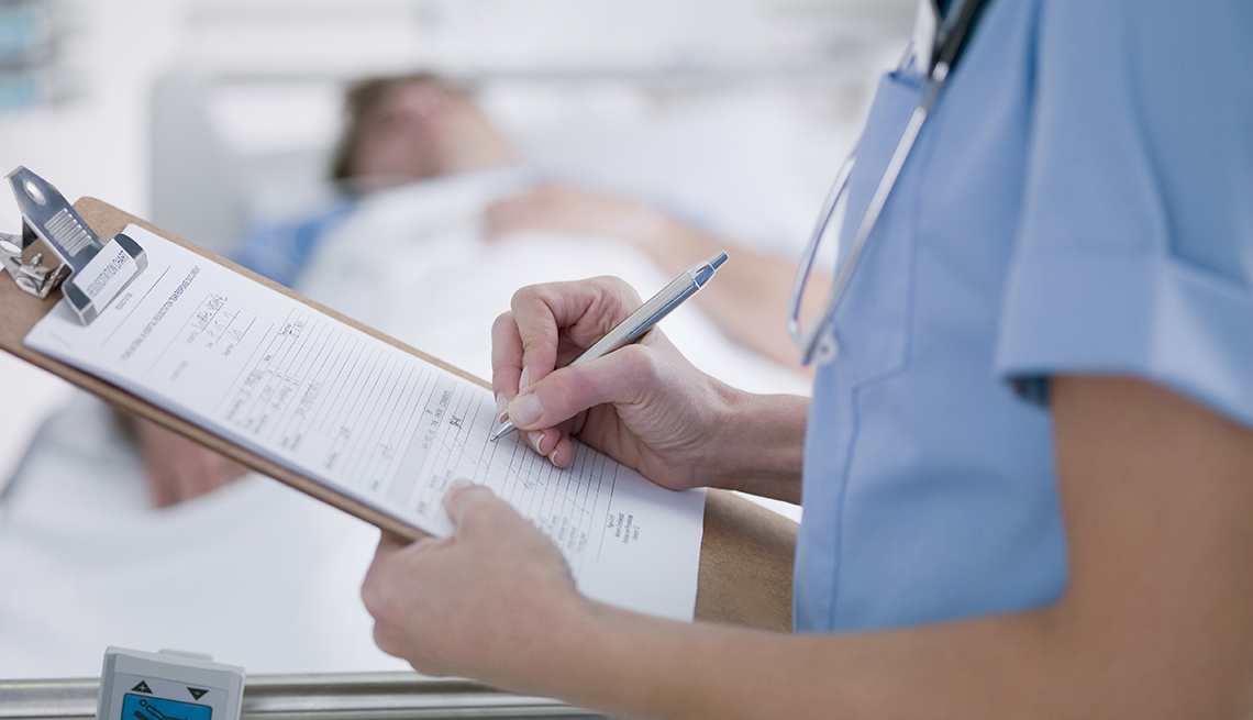 doctor filling out medical form next to a patient in a hospital bed
