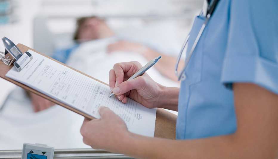 doctor filling out medical form next to a patient in a hospital bed