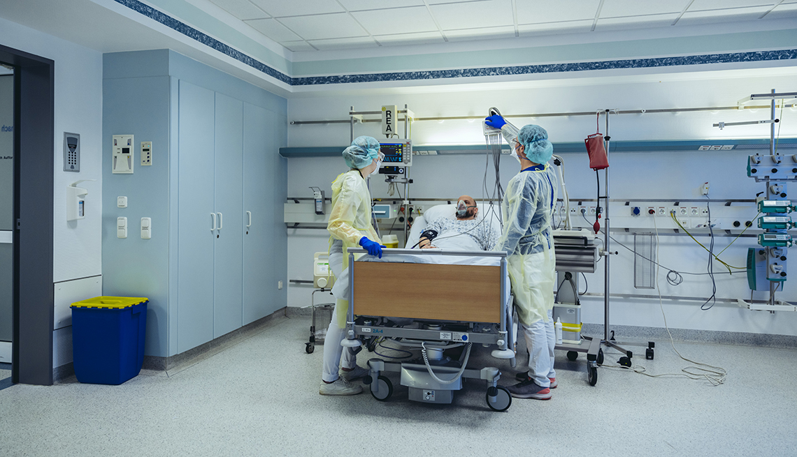 Medical staff caring for a man in a hospital bed.