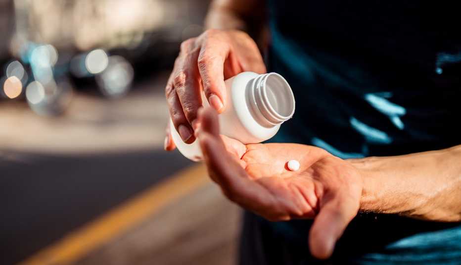 close up of man's hands pouring a pill out of a medicine bottle close up of man's hands pouring a pill out of a medicine bottle