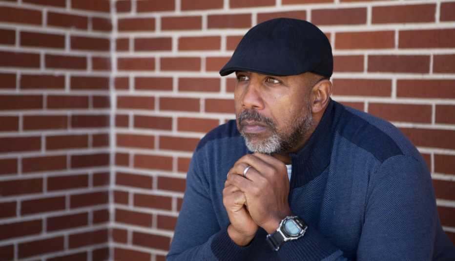 african american man sitting outside near a brick wall