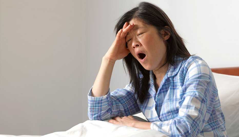 woman in bed, sitting up and yawning