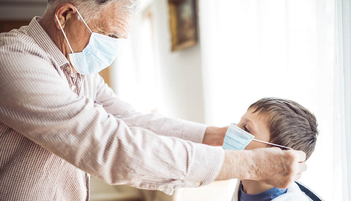 A grandfather putting a mask on his young grandson