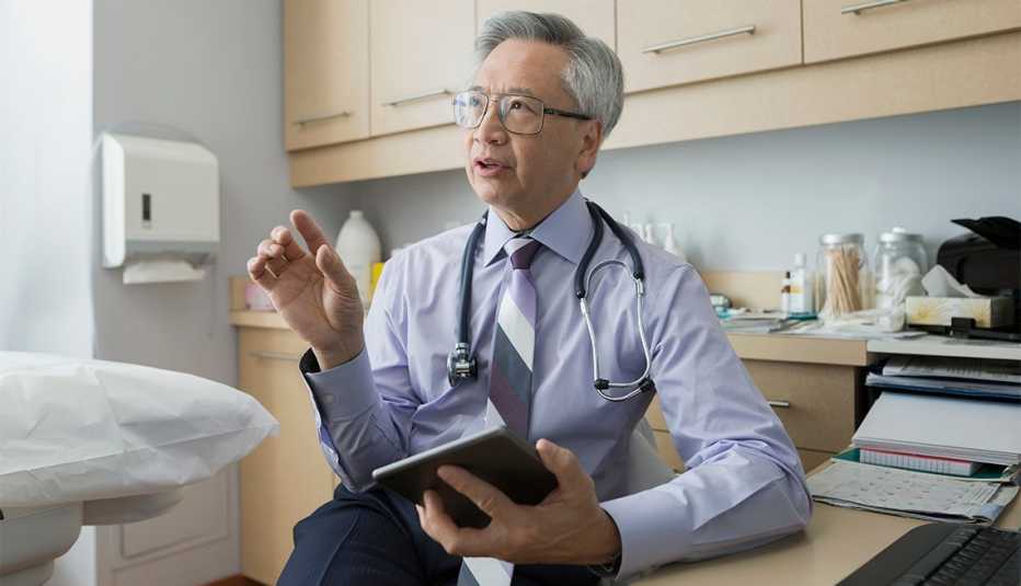 A doctor is in an examining room and talking to an unseen patient
