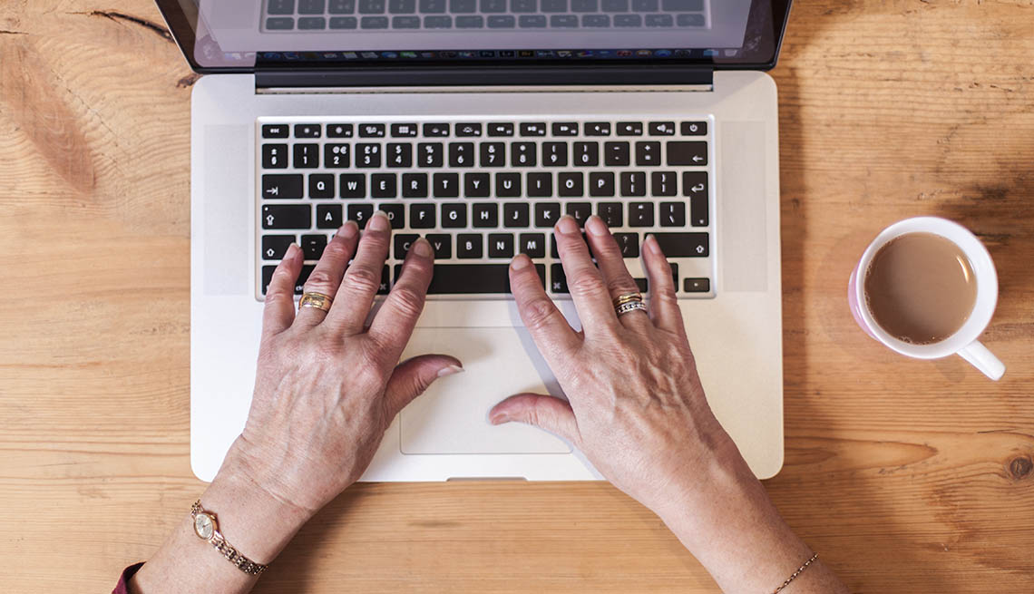women's hands on a laptop computer keyboard, viewed from above