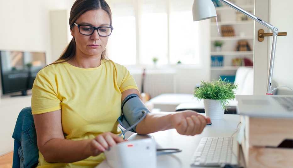 A woman using a device to check her blood pressure at home