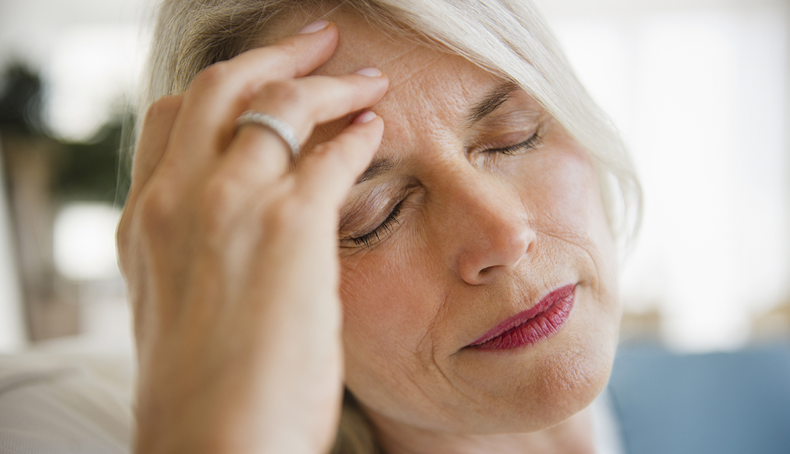 mature blonde woman holding head as if she has a headache