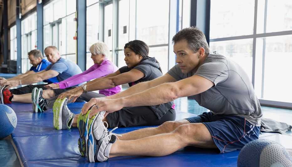 Group of mature adults stretching inside of an exercise studio.
