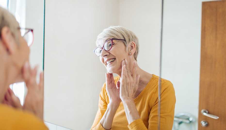 woman in yellow shirt looking at her face in the mirror