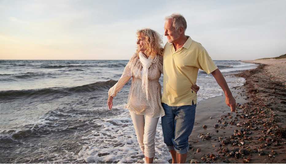 man and woman walking on the beach at sunset