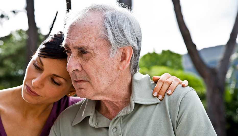 Woman with her arm around her father, both looking sad