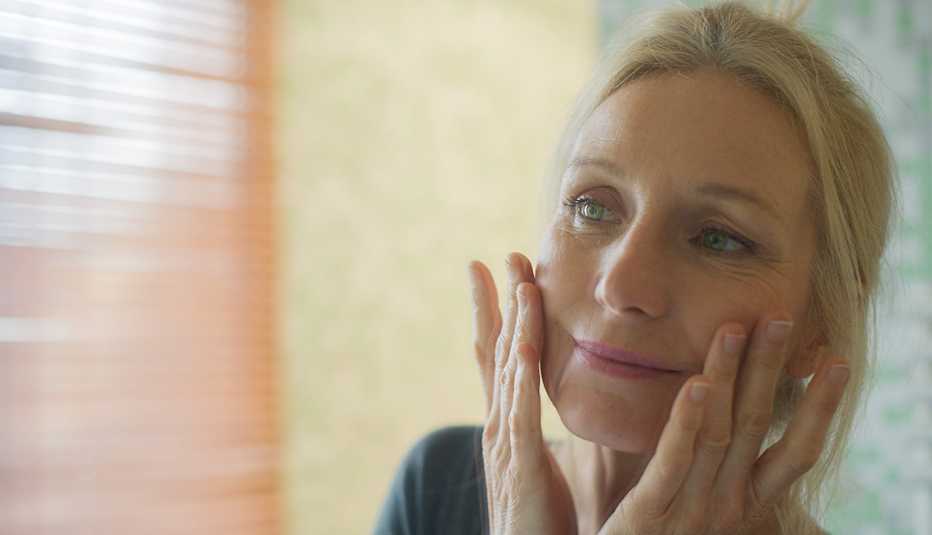 Woman touches her face as she examines her eyes