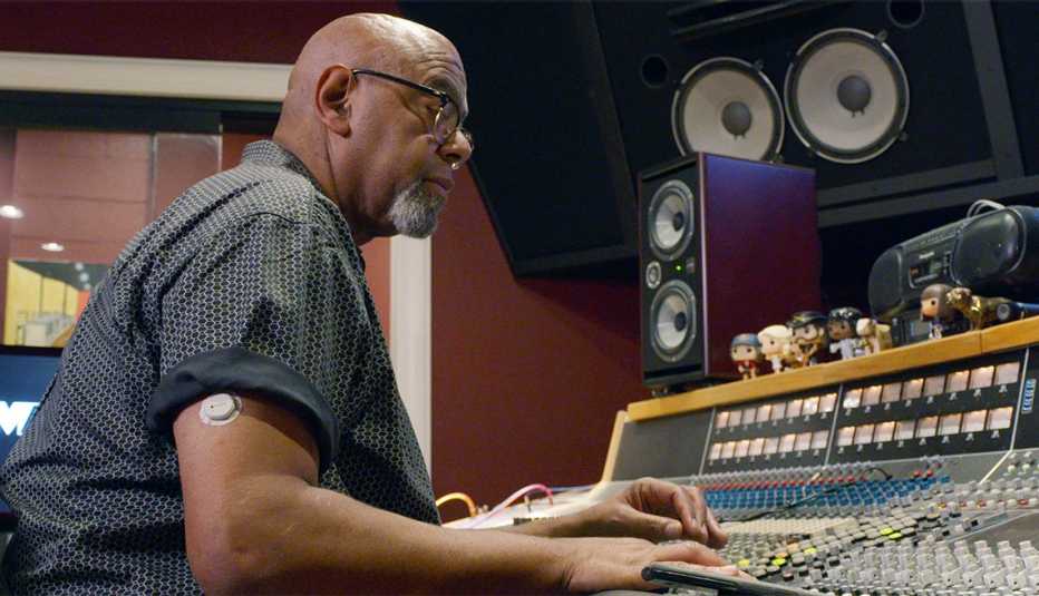 man working in a recording studio wearing a continuous glucose monitor on his upper arm