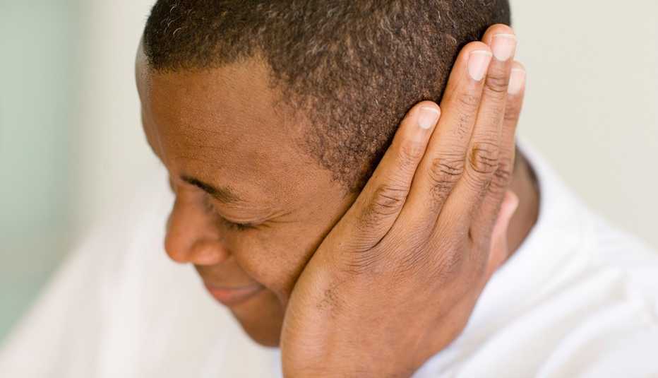 man holding his hand over his ear looking like he is in pain