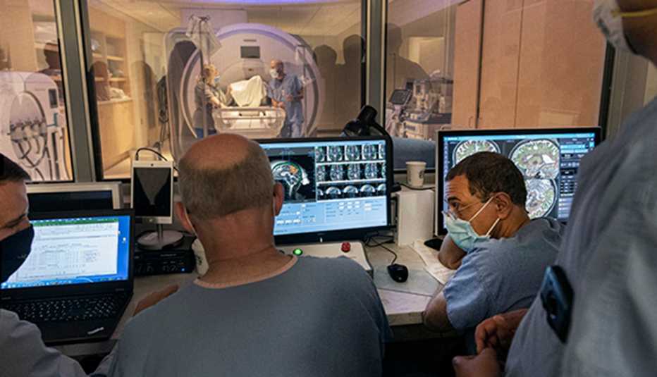 four doctors analyzing a brain scan while patient is getting an ultrasound scan