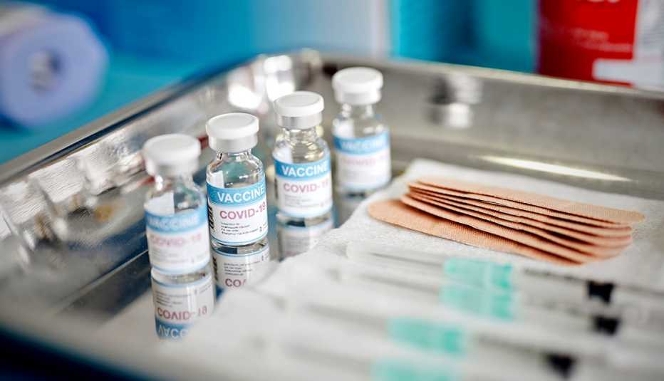 Vials and syringes with COVID-19 vaccine are displayed on a tray