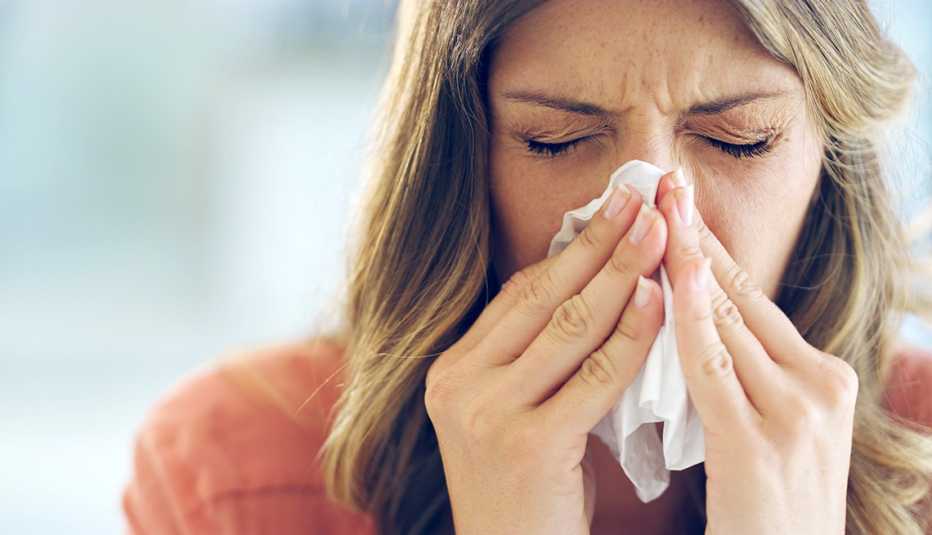 woman sneezing into a tissue