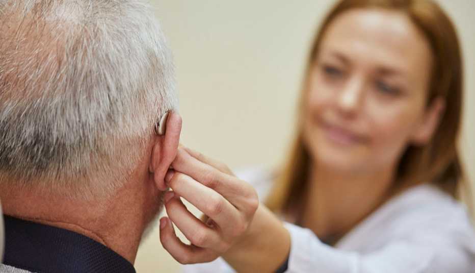 doctor applying hearing aid to man's ear doctor applying hearing aid to man's ear