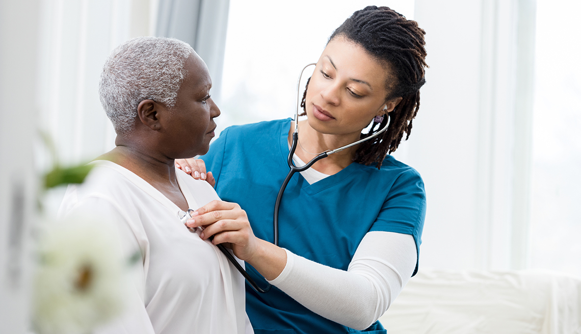 a health care worker listens to the heart and lungs of a female patient