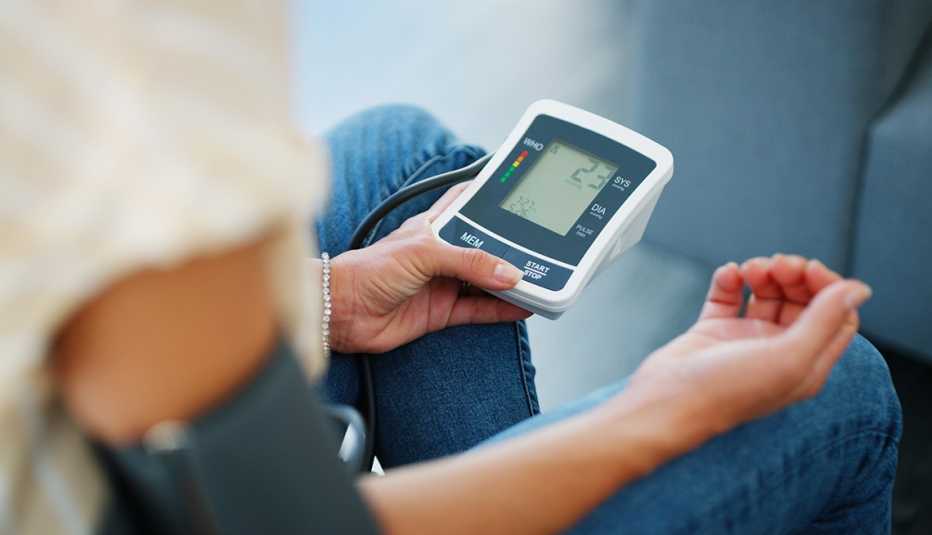 woman checks her blood pressure with an at home monitor