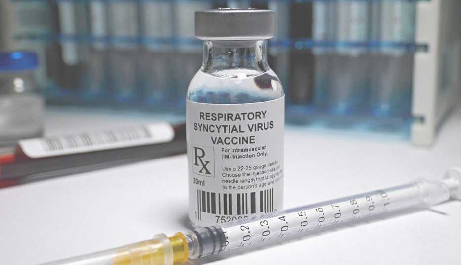small glass vial of r s v vaccine and a syringe next to it on a counter