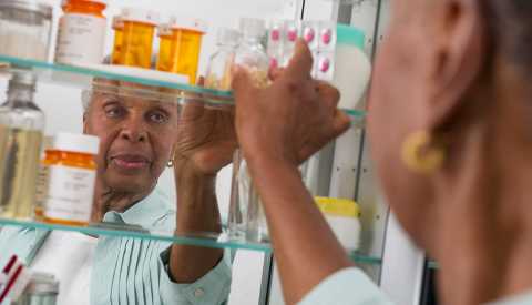 woman reaching into her medicine cabinet woman reaching into her medicine cabinet