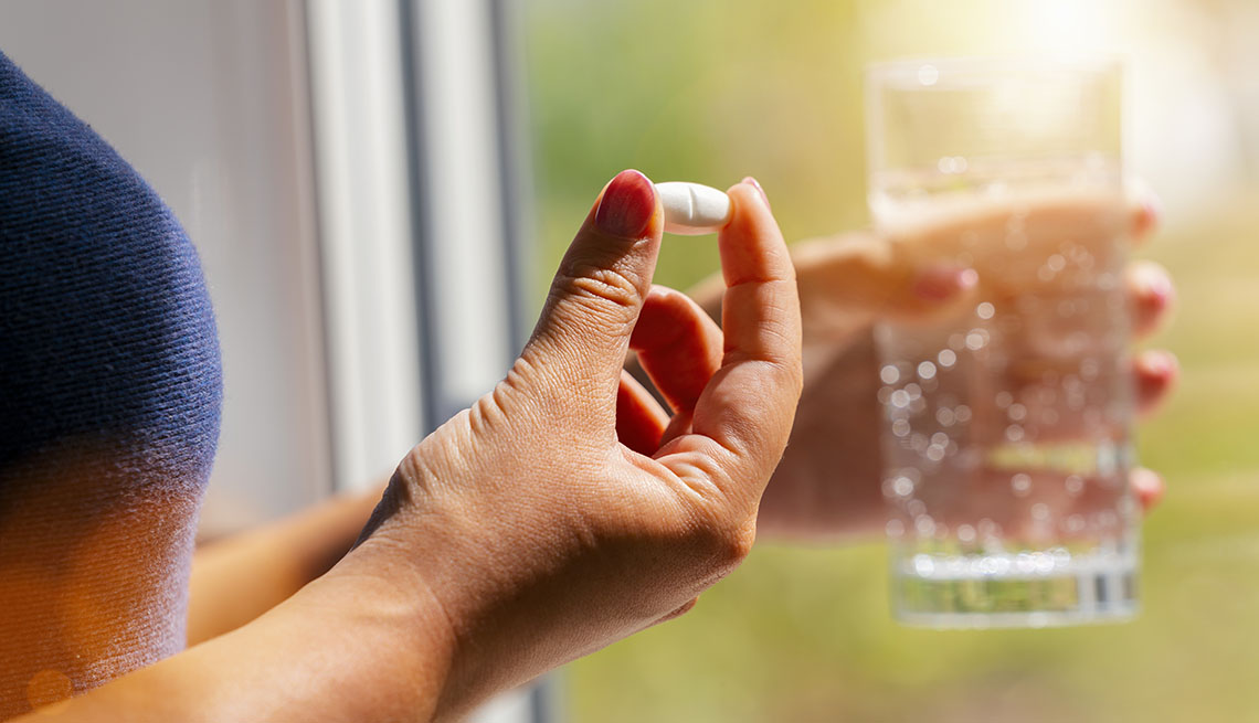 Close-Up Of Woman Holding Tablet And Glass Of Water