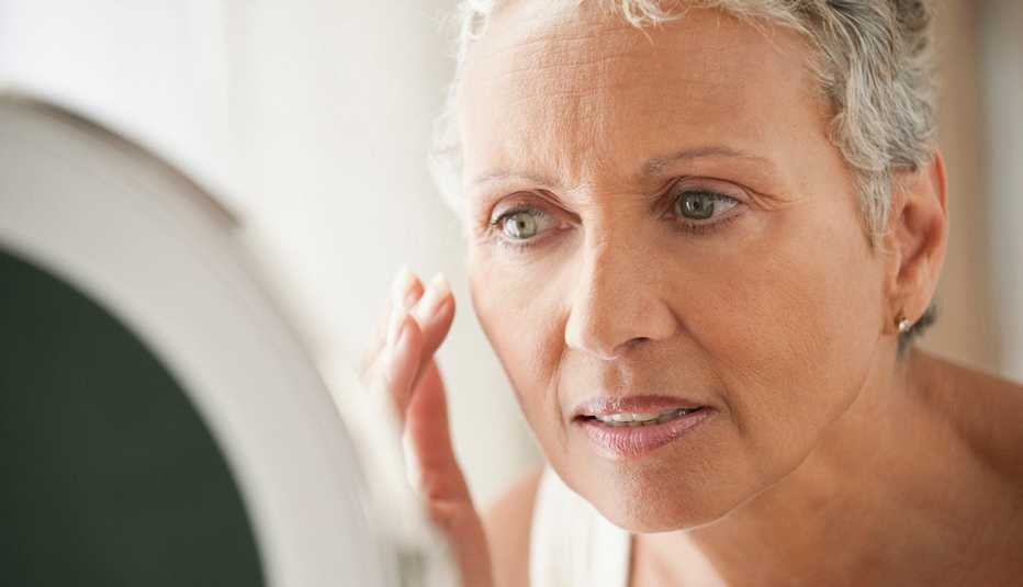 A woman looking at her skin in the mirror