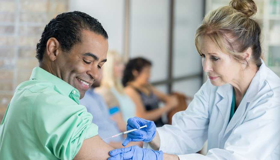 Female doctor administers vaccine to mature man.
