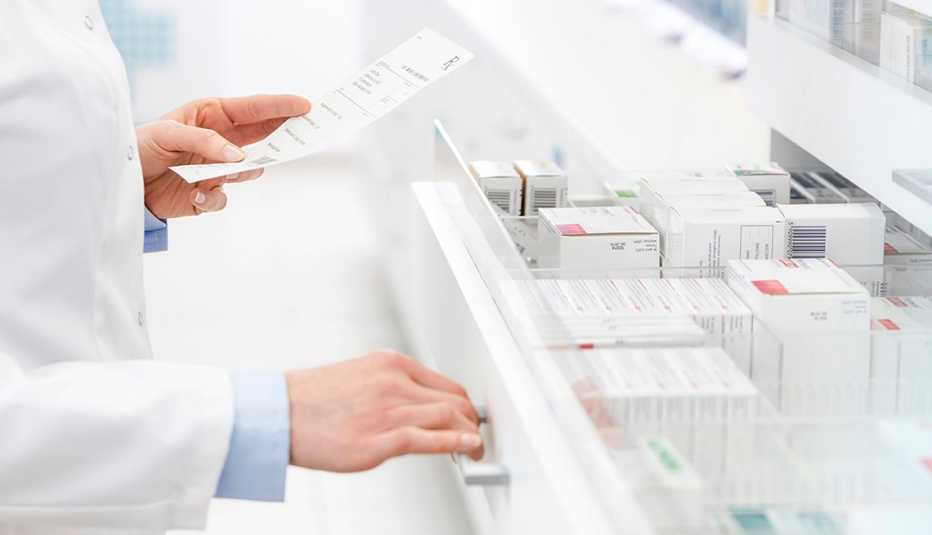 Pharmacist filling prescription in pharmacy. Opening a white drawer full of prescriptions.
